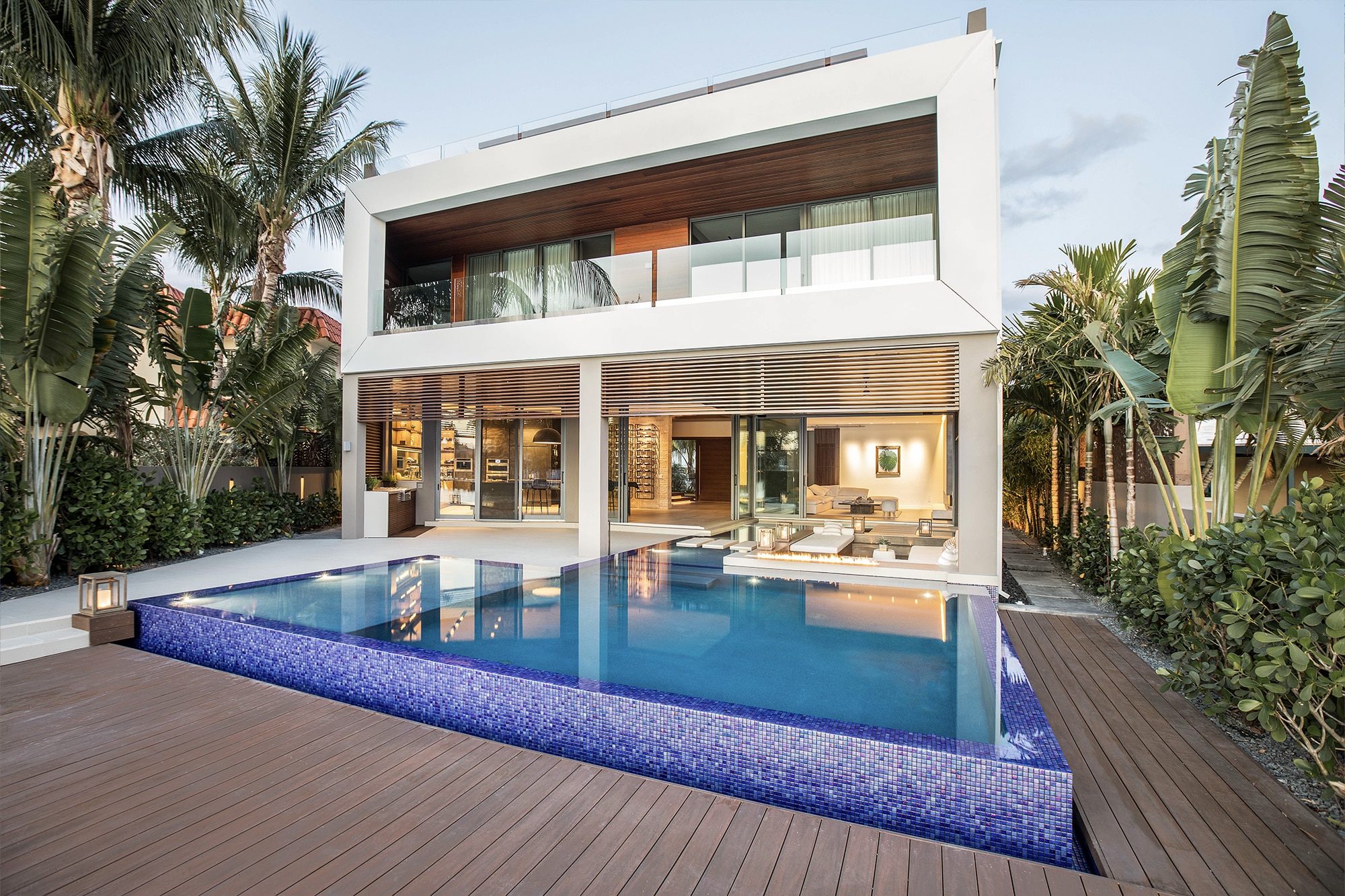 Luxurious outdoor pool area with modern pergola and swing seat, surrounded by lush greenery in naples florida
