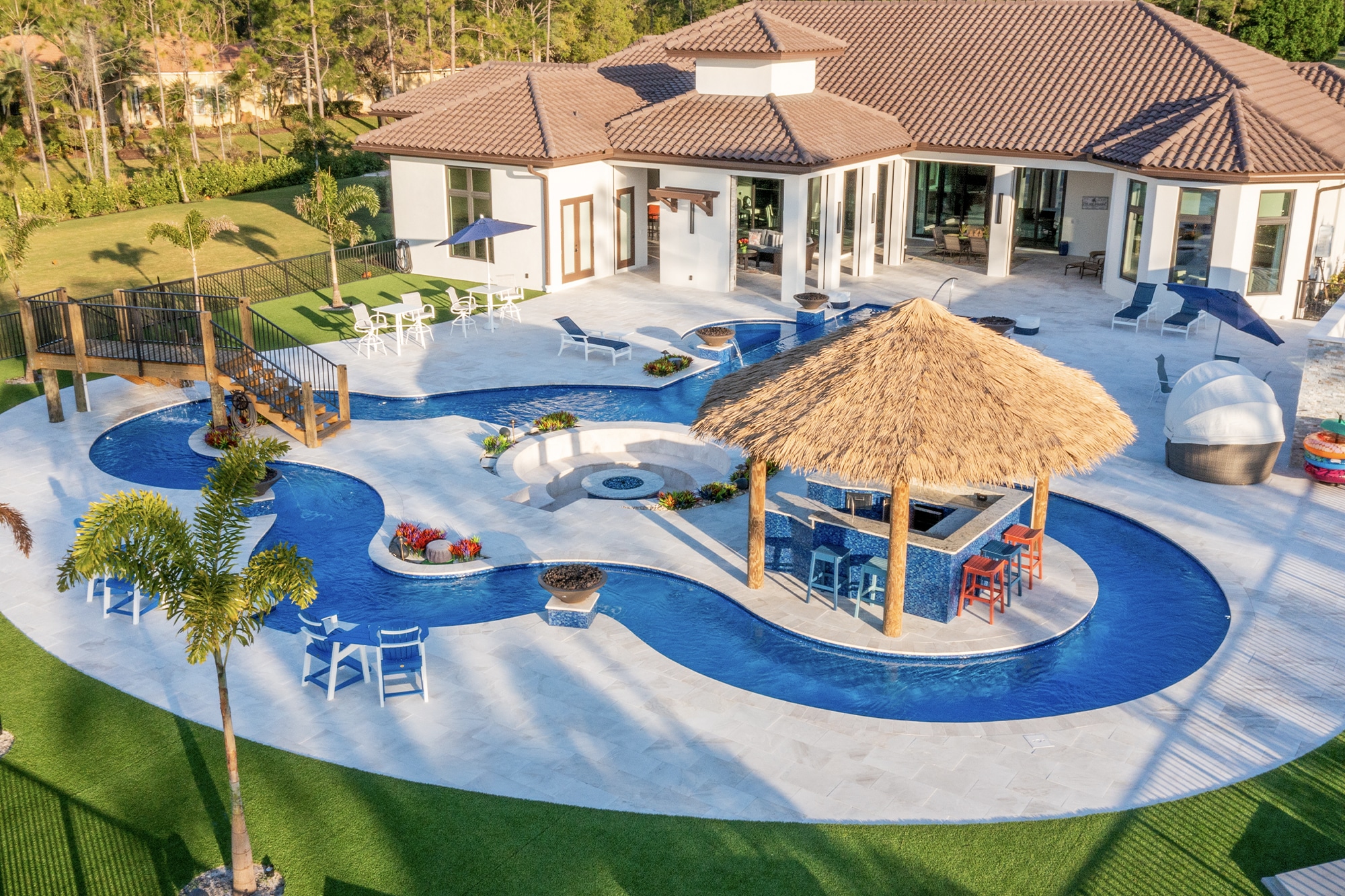Luxury tropical pool with palm trees and inflatables at a resort under a blue sky.