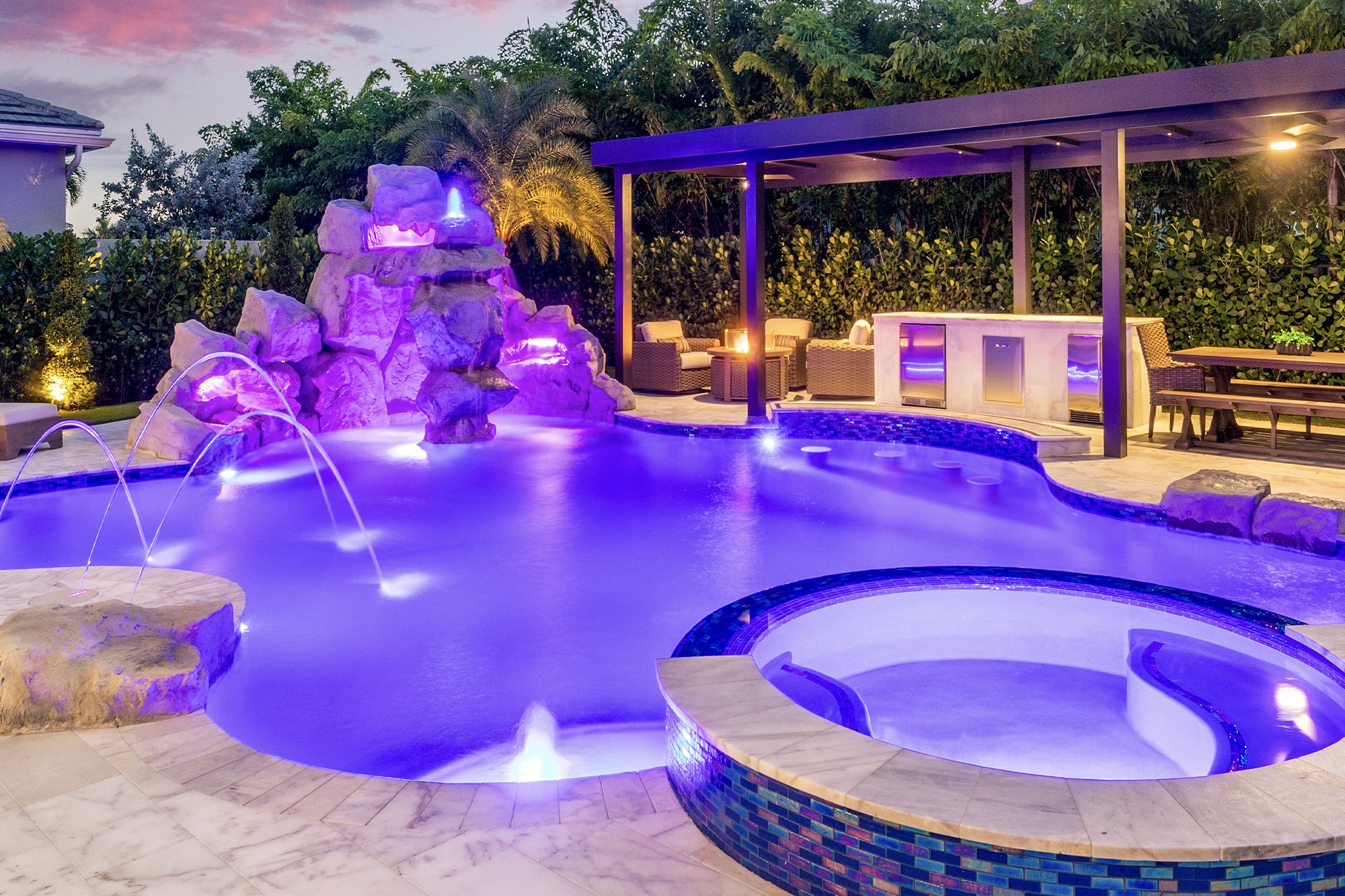 Luxury villa with illuminated pool and palm trees at dusk, highlighting modern architecture and serene ambiance.